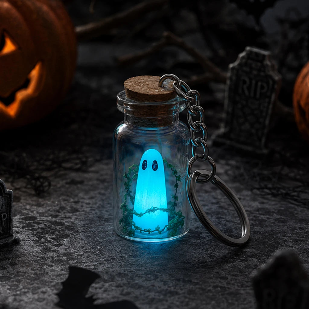 Ghost bottle keychain glowing blue with jack-o'-lanterns behind it