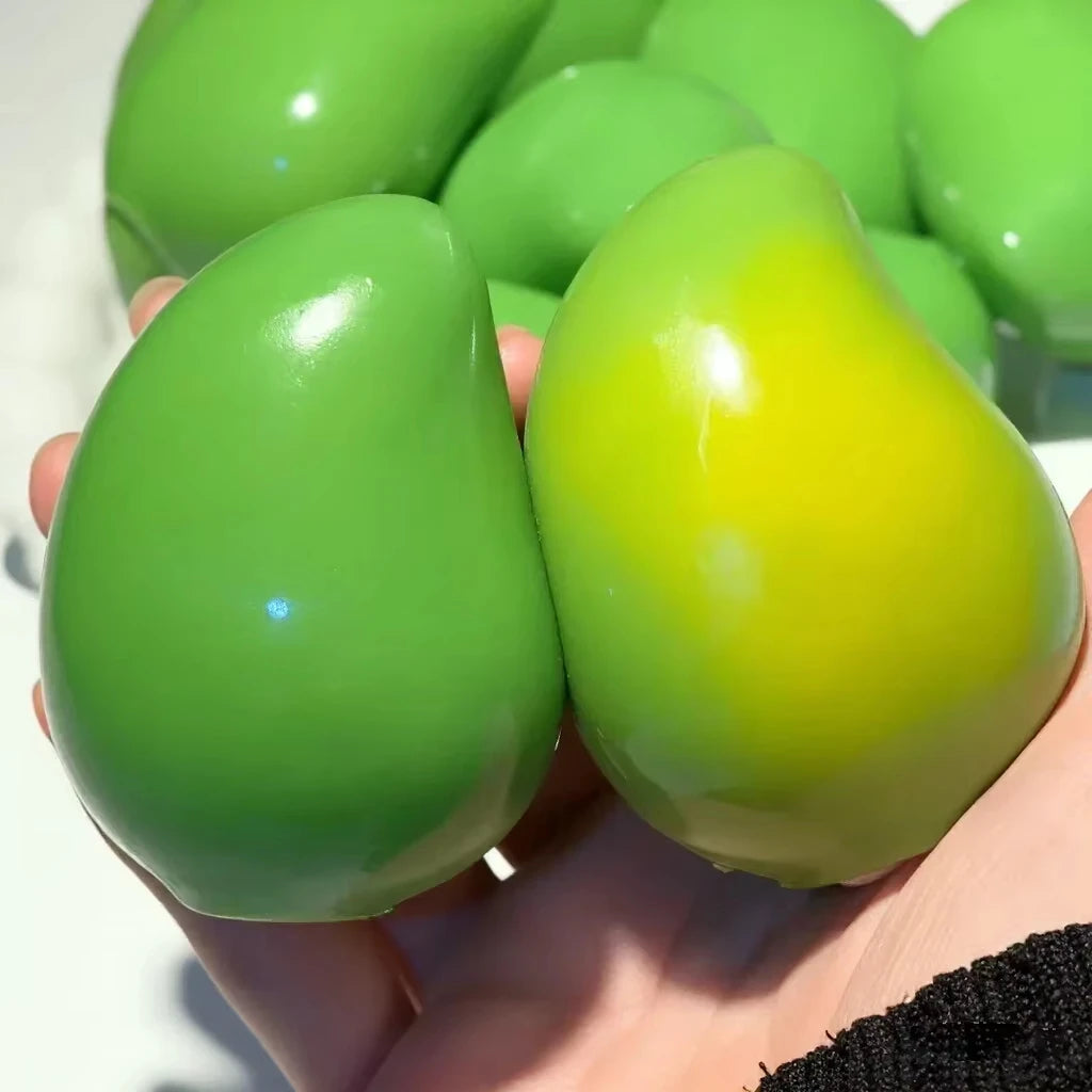 Hand holding a green mango squishy next to a yellow-green one (colors vary)
