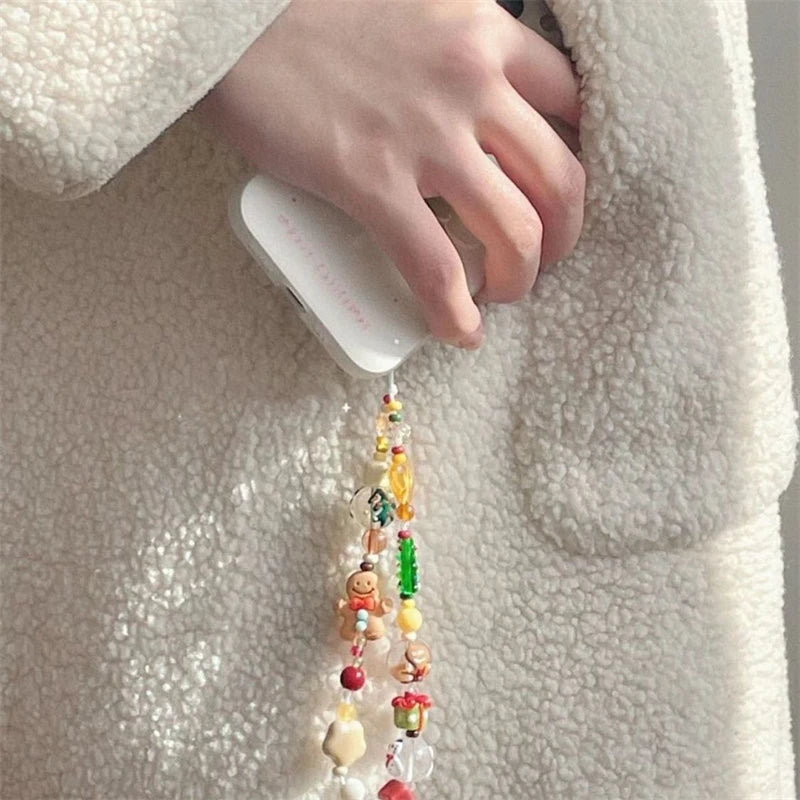 Close-up of the gingerbread and tree beaded phone strap hanging from a phone