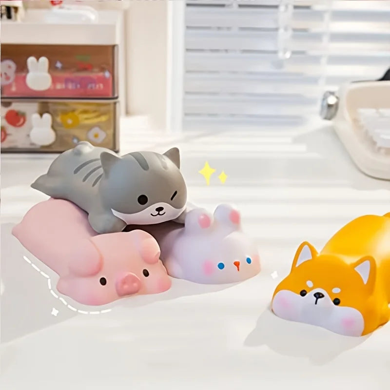 Four silicone wrist rests on a desk: grey cat, pink pig, white rabbit and yellow Shiba