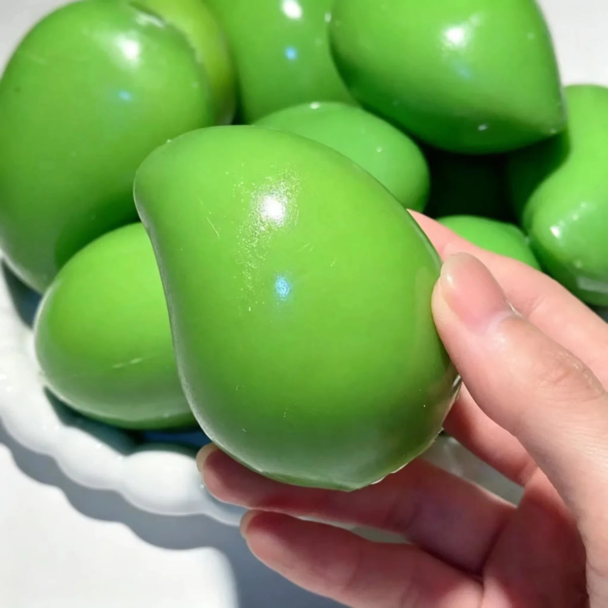 Green mango squishy being gently squeezed in a hand