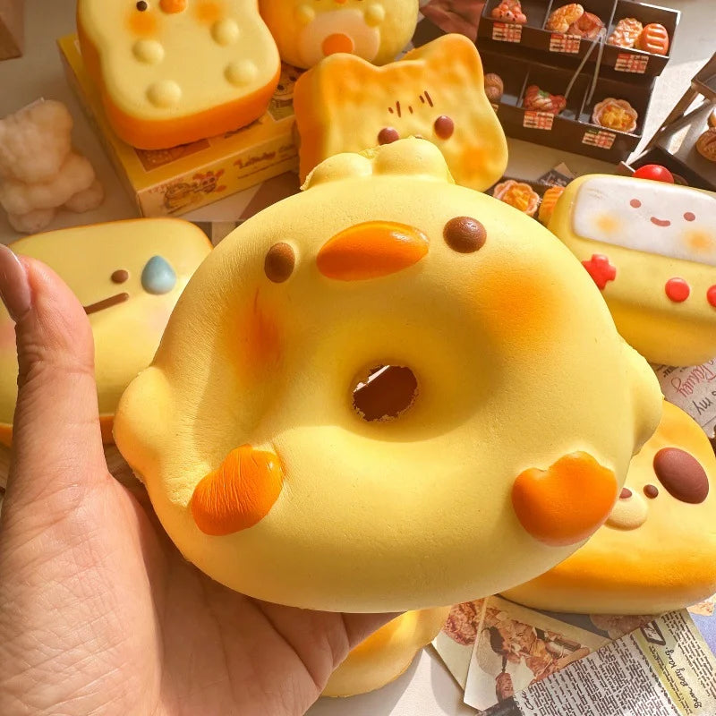 Hand holding a round yellow bird bread bun squishy with an orange beak and feet