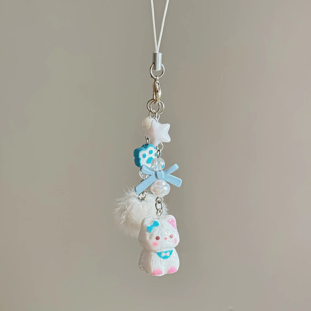 Blue cat bead phone strap with a blue bow, paw bead, star bead, pom-pom and white cat charm