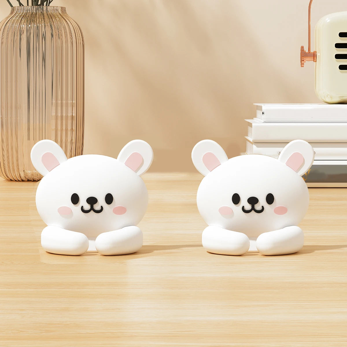 Two white rabbit cable clips with pink ears on a wooden desk