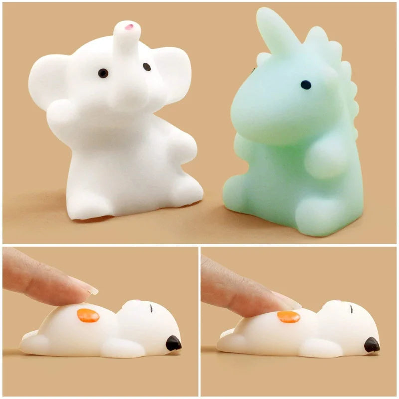 Close-up of a white elephant and mint dinosaur mochi squishy, and a finger pressing a soft mochi puppy
