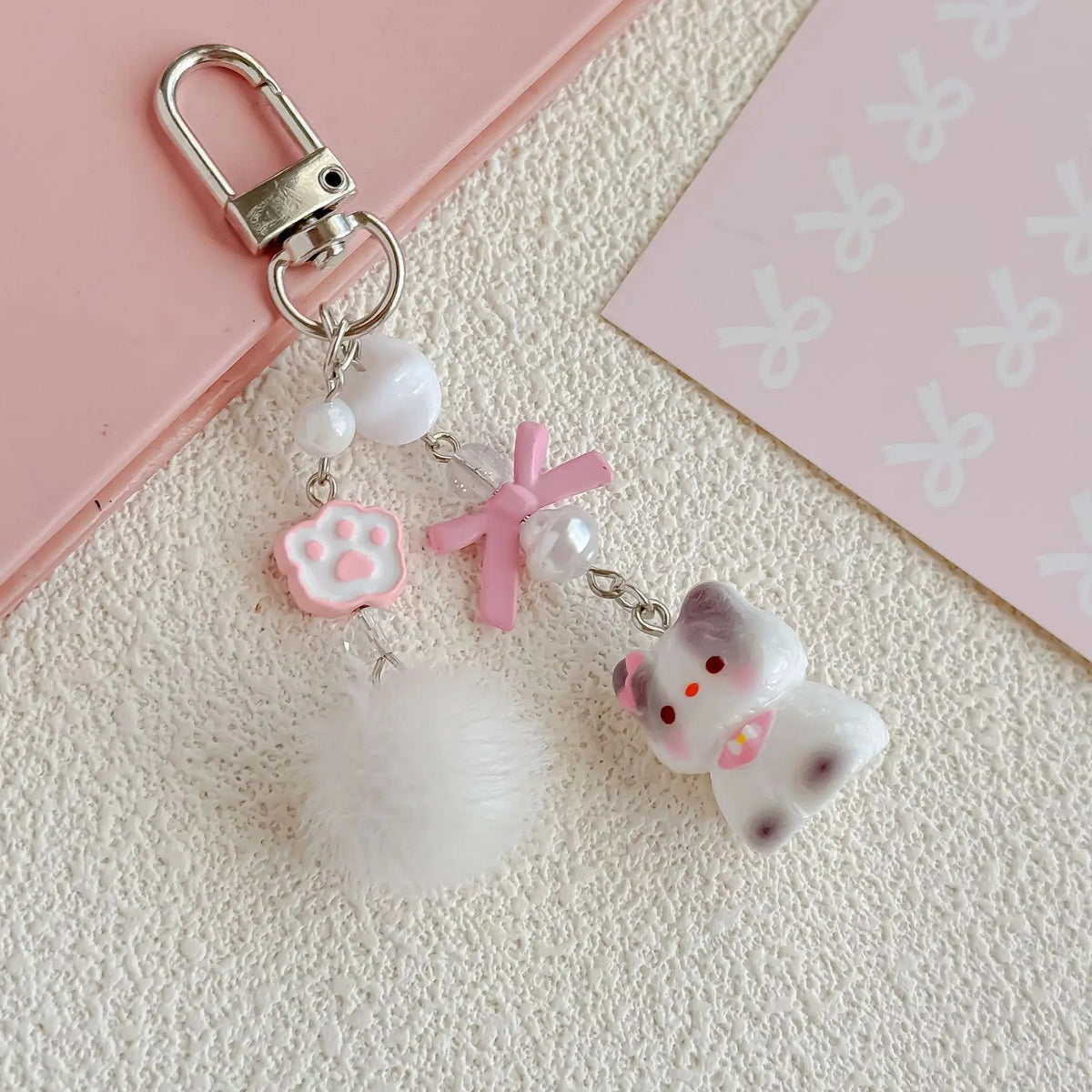 Close-up of the pink cat bead strap charms: paw bead, pink bow, pom-pom and cat