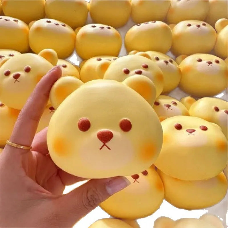 Hand holding a bear-face bread bun squishy in front of a pile of bear buns