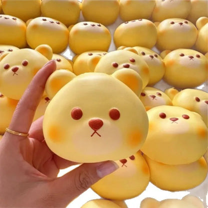 Hand holding a bear-face bread bun squishy in front of a pile of bear buns