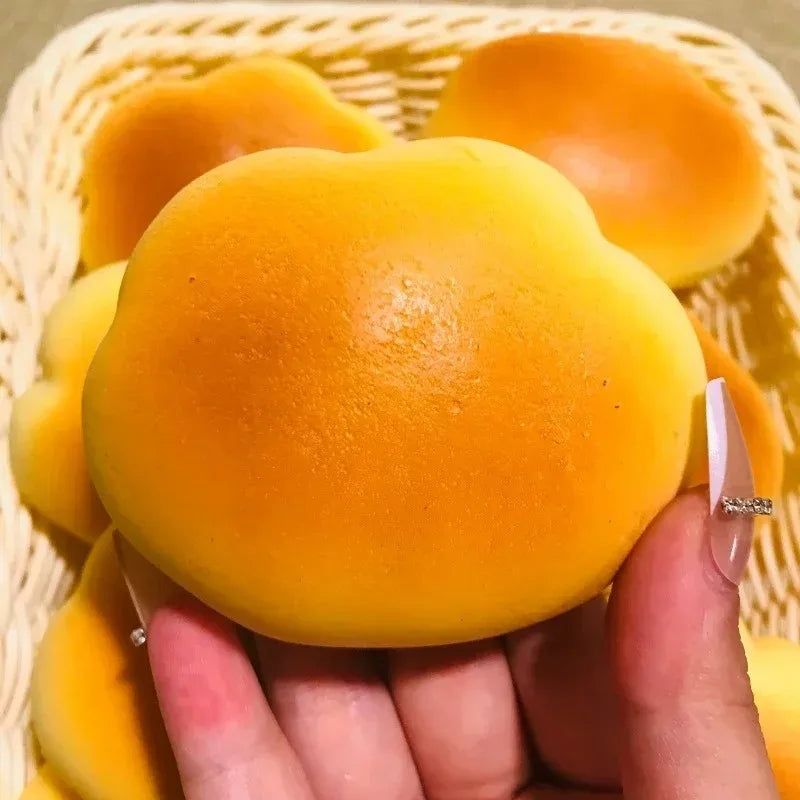 Hand holding a caramel cloud bread squishy over a basket of cloud bread squishies