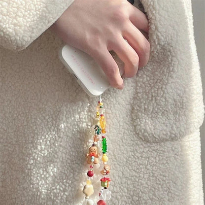 Close-up of the gingerbread and tree beaded phone strap hanging from a phone