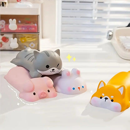Four silicone wrist rests on a desk: grey cat, pink pig, white rabbit and yellow Shiba