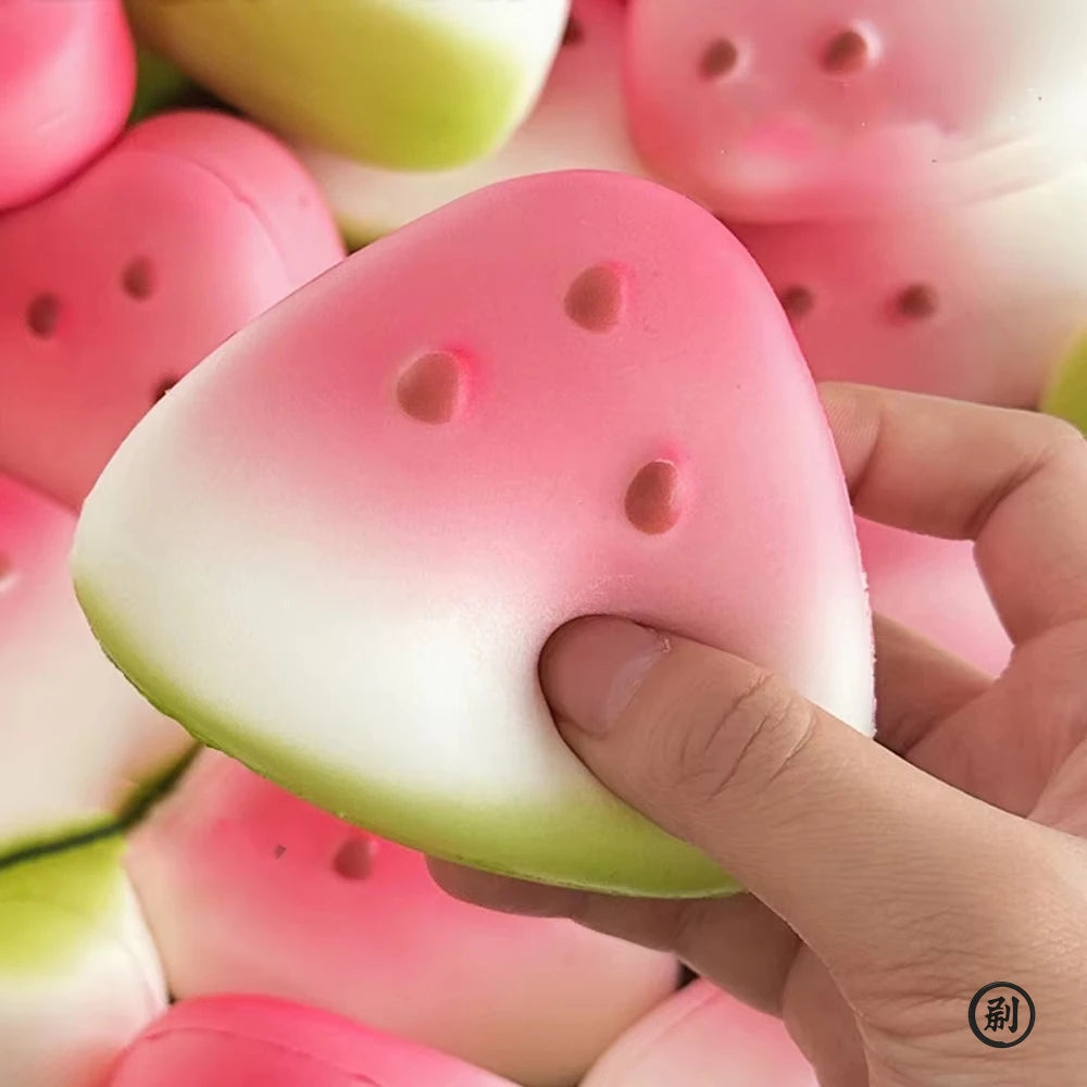 Hand squeezing a pink and green watermelon slice squishy