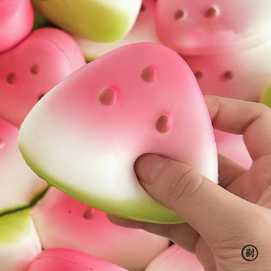Hand squeezing a pink and green watermelon slice squishy