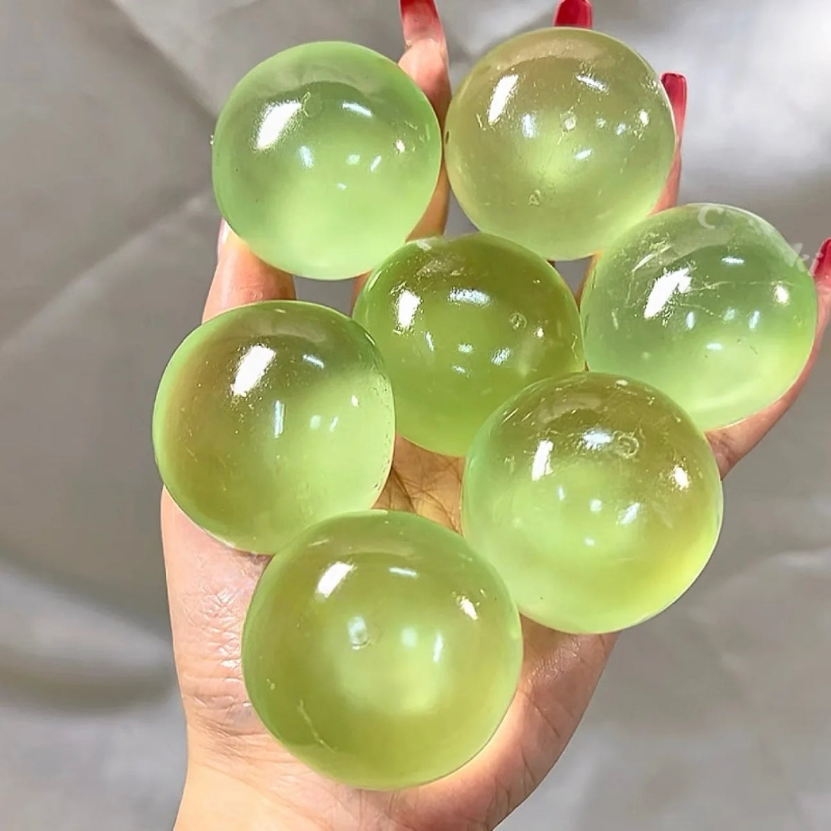 Seven lime jelly squeeze balls held together in one hand, for a sense of size