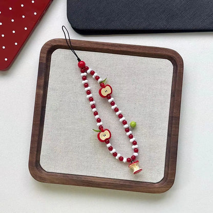 Apple beaded charm strap laid flat on a linen tray
