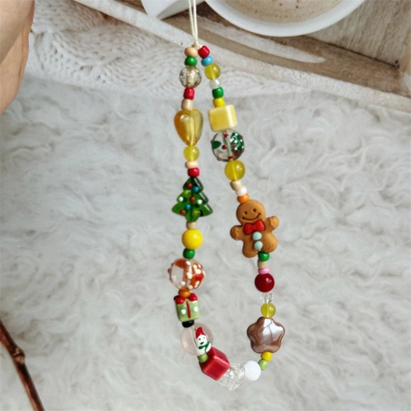 Beaded phone strap with gingerbread man and Christmas tree charms on a fuzzy white blanket