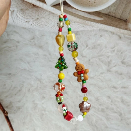 Beaded phone strap with gingerbread man and Christmas tree charms on a fuzzy white blanket