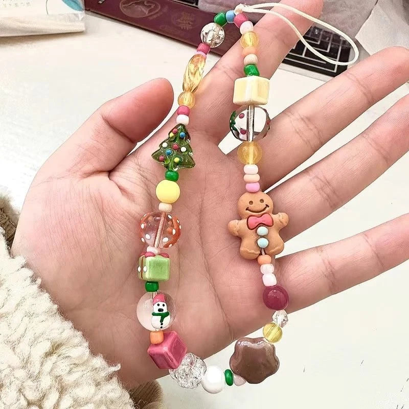 Gingerbread and Christmas tree beaded phone strap held in an open hand