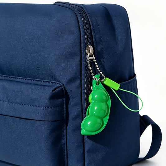 Edamame pop squishy keychain clipped to a backpack zipper