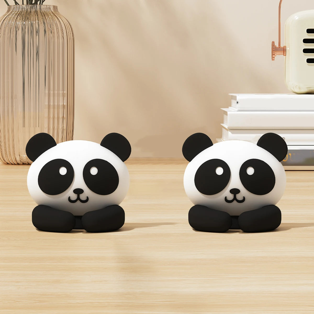 Two black and white panda cable clips on a wooden desk