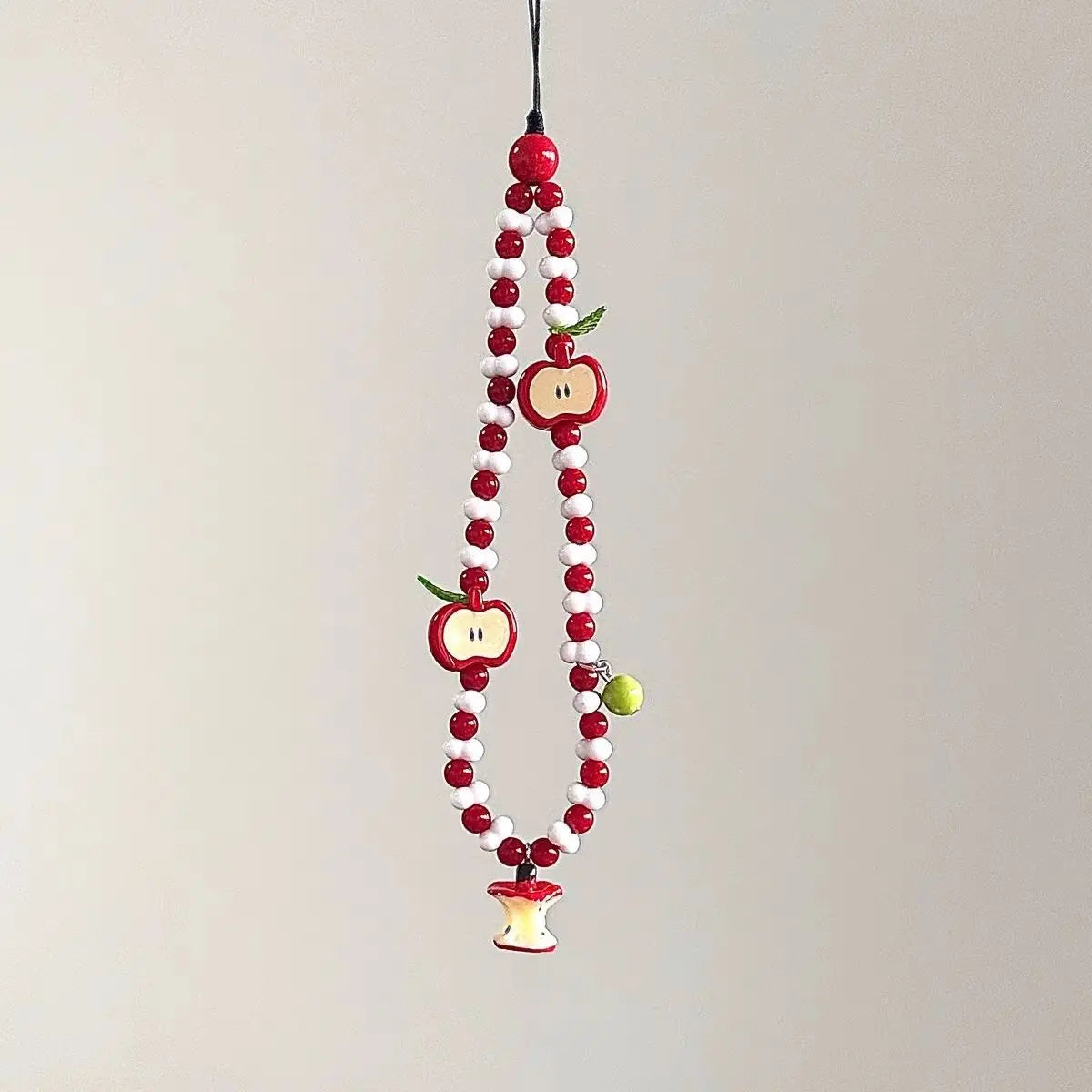Red and white beaded phone charm strap with apple charms