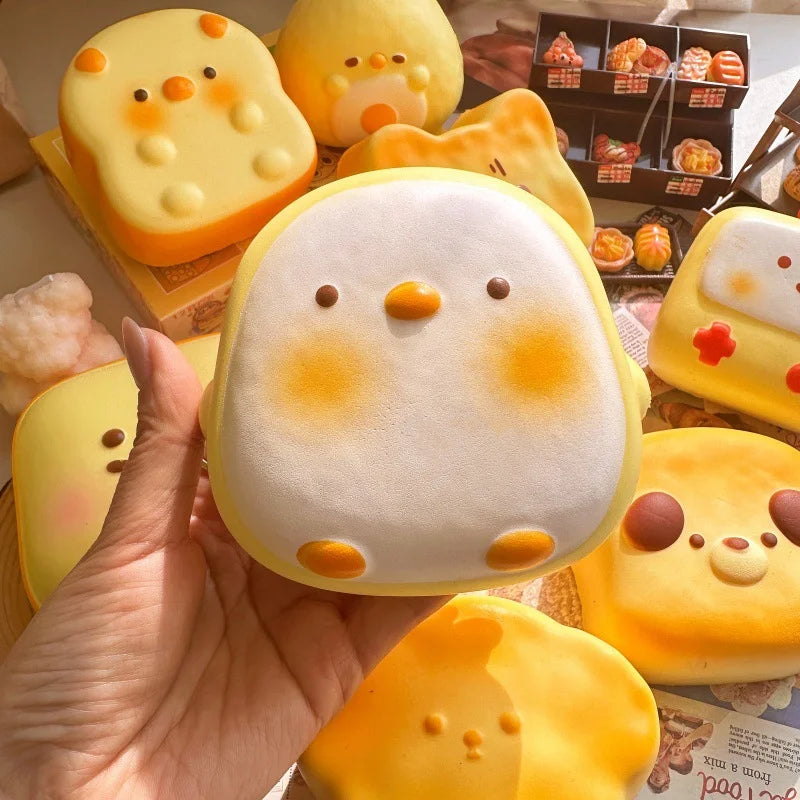 Hand holding a white and yellow bird bread bun squishy with rosy cheeks
