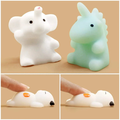 Close-up of a white elephant and mint dinosaur mochi squishy, and a finger pressing a soft mochi puppy