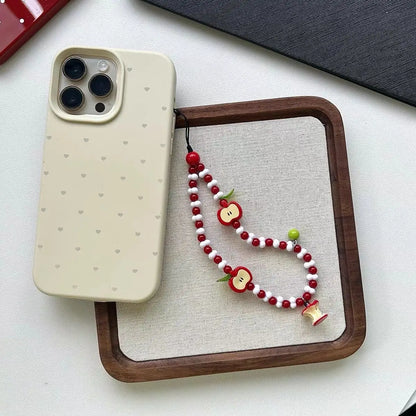 Apple beaded charm strap next to a phone