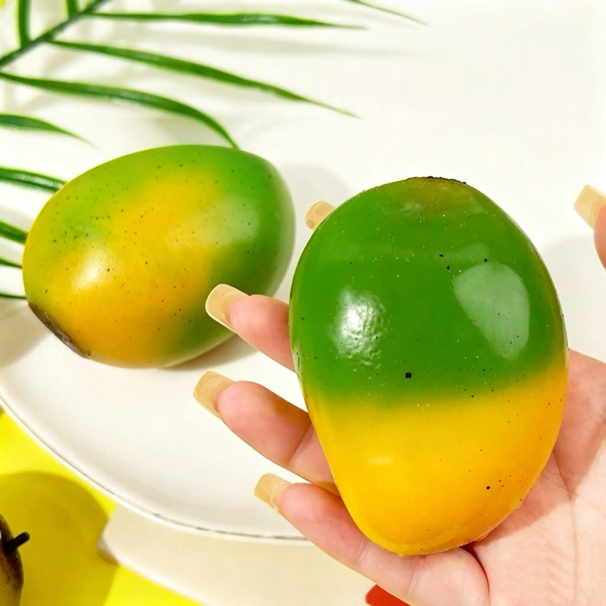 Two mango squishies in orange-green and green-yellow shades on a plate