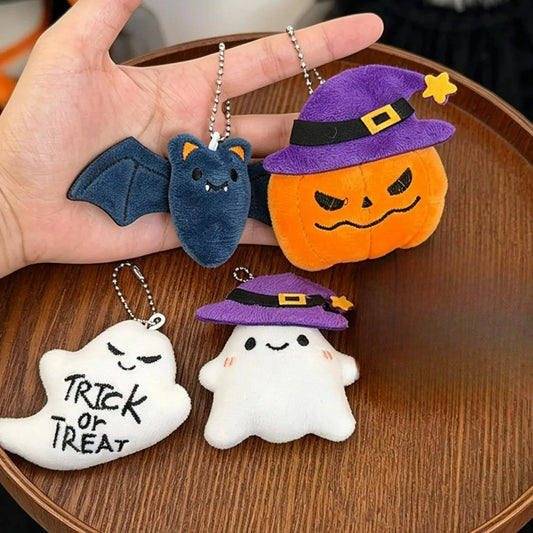 Witch-hat pumpkin plush keychain (orange pumpkin with a purple witch hat) held in a hand, shown with other Halloween plush styles