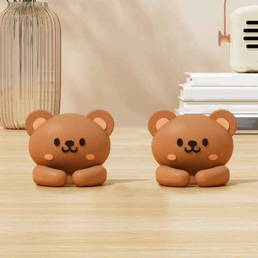 Two brown bear cable clips sitting on a wooden desk
